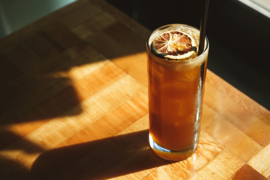 Café spritz com limão siciliano e gelo sobre uma tábua de madeira, iluminada por luz natural, ideal para apreciar em momentos de lazer.