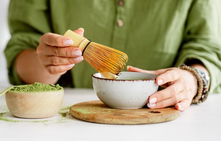 Pessoa preparando chá verde com chá e utensílios de cozinha, focada na tradição natural e saudável na preparação de bebidas. Ideal para quem busca bem-estar e cultura de chá.